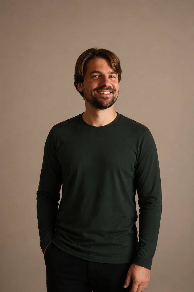 Macklin Buckler, studio portrait in a forest crewneck against a warm taupe backdrop
